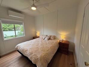 Relax in a serene bedroom with a large bed, two bedside tables, and a window offering a view.