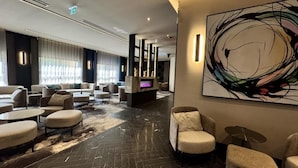 A modern hotel lobby with a fireplace, comfortable seating, and a large abstract painting. - Aste Hotel (St. Julian's)