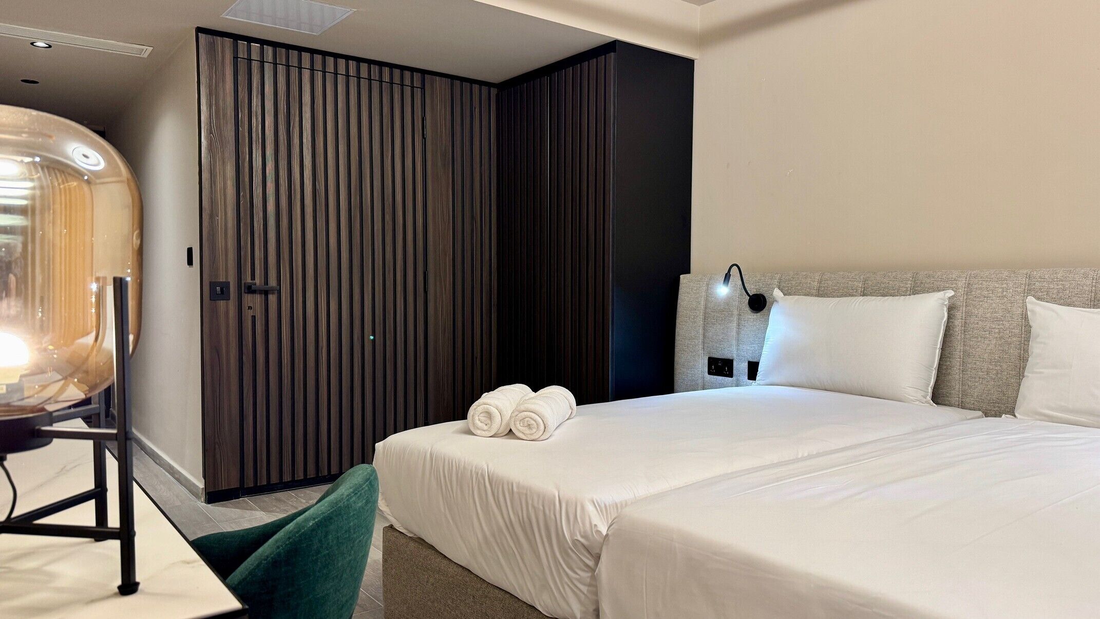 Een moderne hotelkamer met een bed, een bureau en een kledingkast.