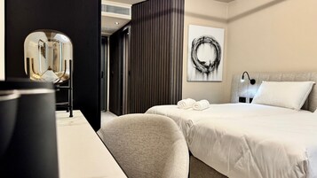 Una habitación de hotel con una cama, un escritorio, una silla, un espejo y una obra de arte en la pared.