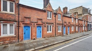 Une rangée de maisons de ville aux façades en briques rouges, avec des portes bleues et des fenêtres à encadrements blancs.
