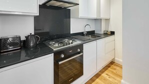 A modern kitchen with white cabinets, a black countertop, a Bosch oven, and a gas stove. - Host Stay Eton House (Windsor)