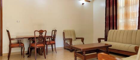 A living room with a dining table, chairs, a sofa, and a coffee table.