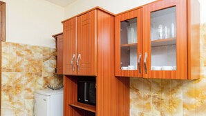 A kitchen with wooden cabinets, a microwave, and a tiled backsplash. - Atlas Residence (Kigali)