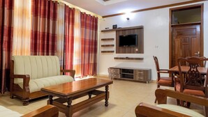 A living room with a sofa, wooden coffee table, and dining table with chairs. - Atlas Residence (Kigali)