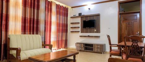 A living room with a sofa, wooden coffee table, and dining table with chairs.