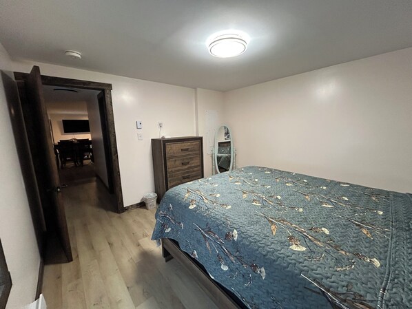 Een slaapkamer met een bed, een kaptafel, een spiegel en een deur naar een andere kamer.