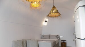 A modern, minimalist bedroom with a sofa, bed, and a unique woven light fixture. - Imarkellis Pyrgos Traditional House and Belfry Charm with Courtyard in Santorini (Pyrgos Kallistis)
