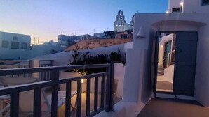 A balcony with a railing, a door, and a view of buildings in the background. - Imarkellis Pyrgos Traditional House and Belfry Charm with Courtyard in Santorini (Pyrgos Kallistis)