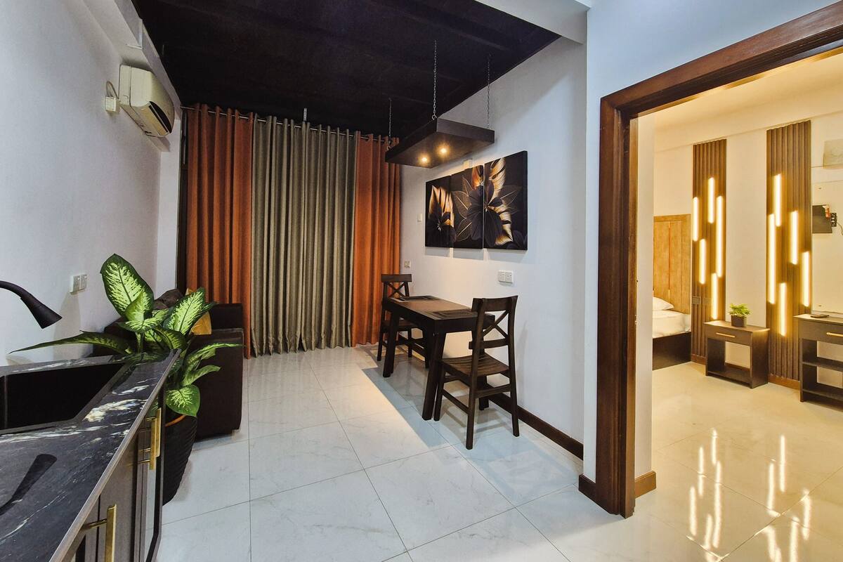 Un interior moderno con zona de comedor, una planta y mostrador de cocina.