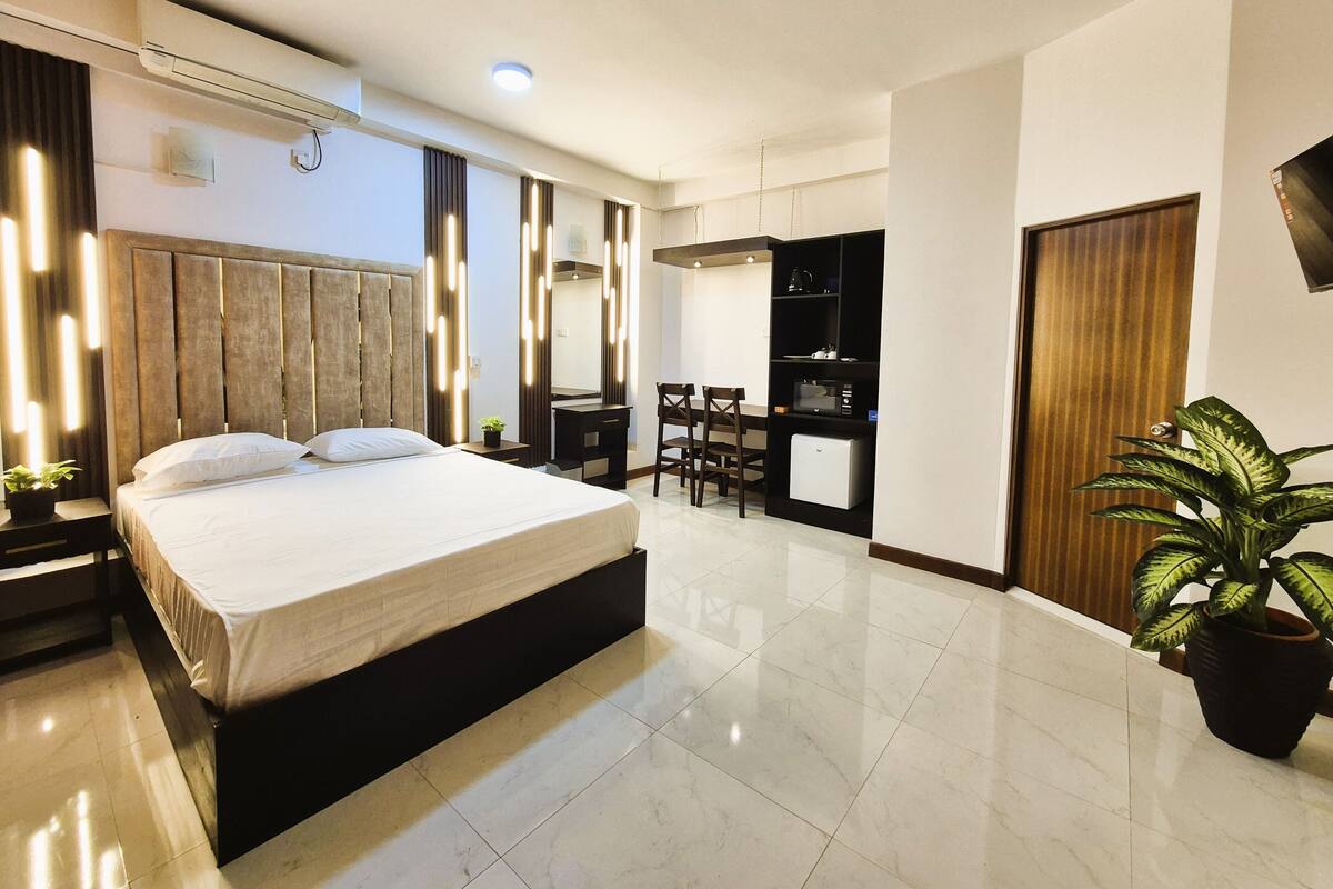 Una habitación de hotel moderna con una cama grande, un escritorio y un armario empotrado.