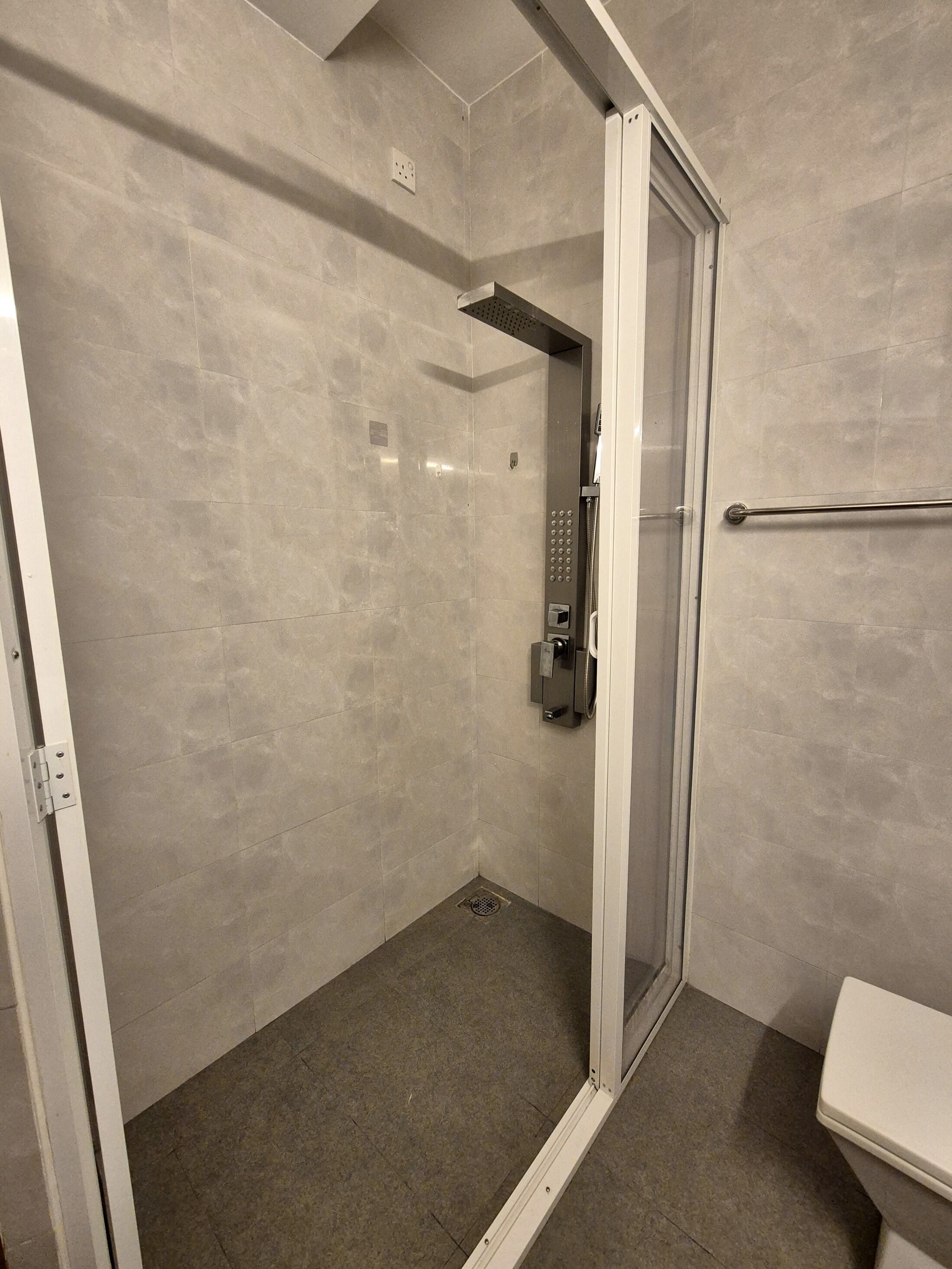 A modern bathroom with a glass-enclosed shower, a white sink, and a towel rack.