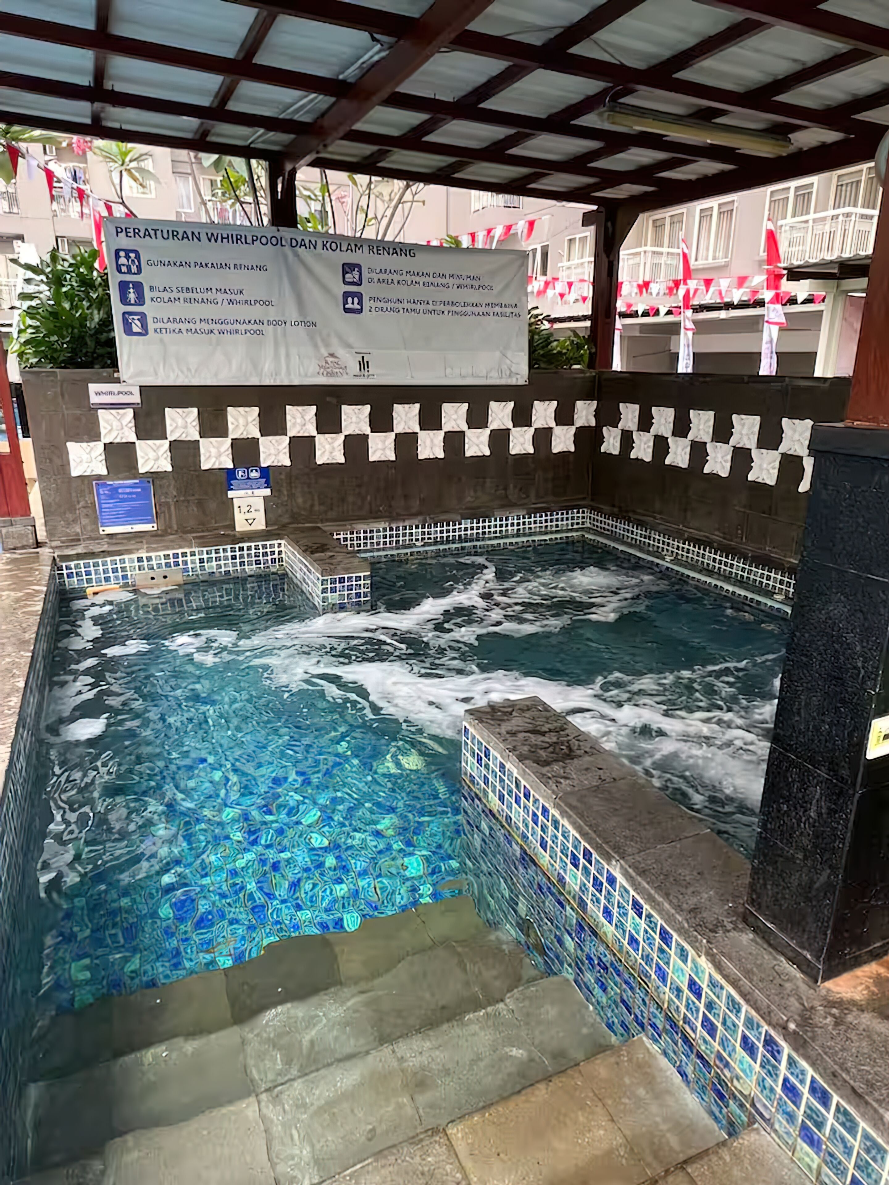 Une piscine à jets avec un bord carrelé et un panneau indiquant qu’il s’agit d’un espace dédié aux jets.