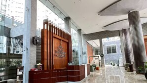 A spacious lobby with a reception desk, marble flooring, and large windows offering views of the city.