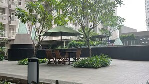 An outdoor seating area with a table and chairs, surrounded by potted plants and a small water feature.