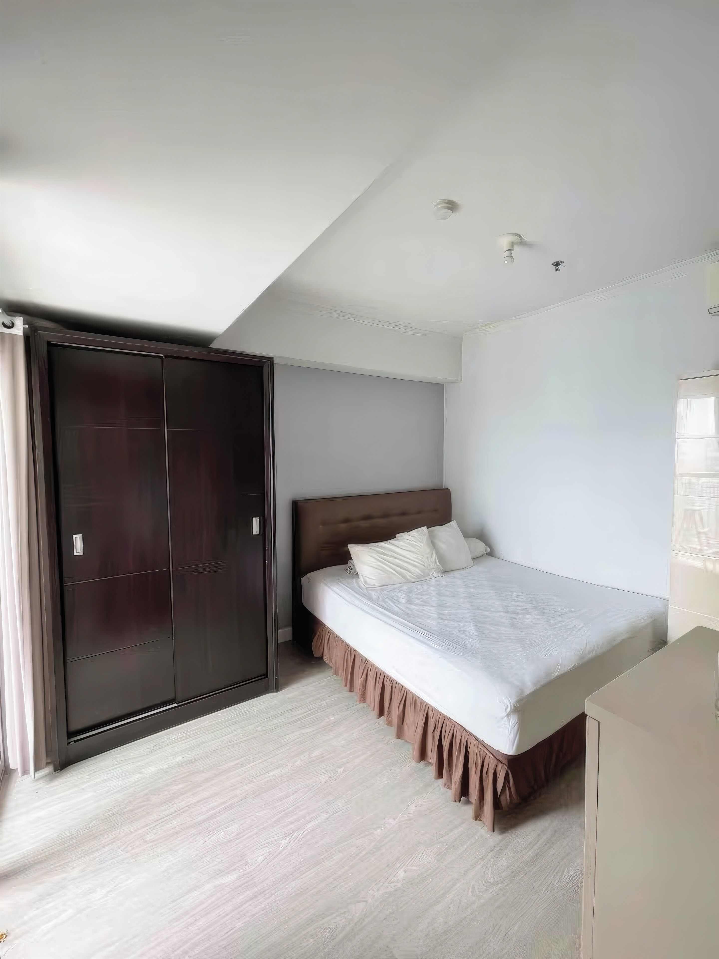 A bedroom with a bed, a wardrobe, and a desk.