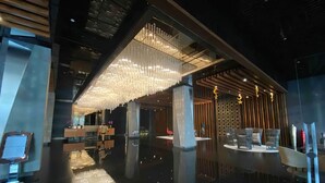 A modern lobby with a reflective floor, a reception desk, and a seating area with tables and chairs.