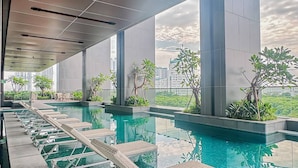 A modern indoor pool with lounge chairs and potted plants, large windows, and a view of city buildings. - Premium Luxury Menara Jakarta Residence (Jakarta)