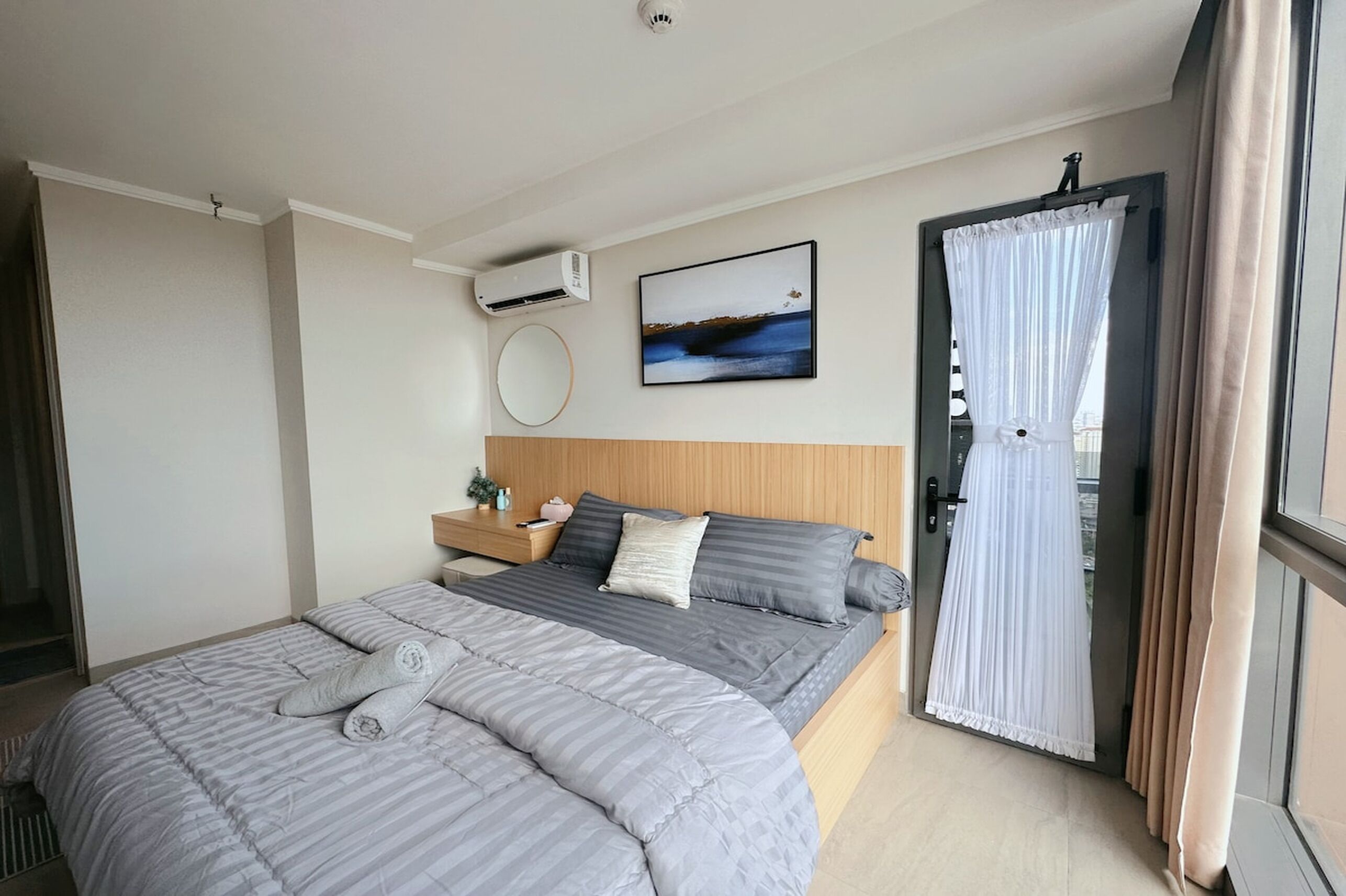 Un dormitorio moderno con una cama grande, una mesita de noche, aire acondicionado instalado en la pared y una ventana con cortinas.
