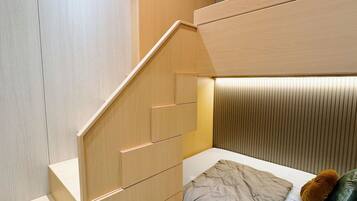 A modern bedroom with a built-in bed, wooden wardrobe, and a staircase.