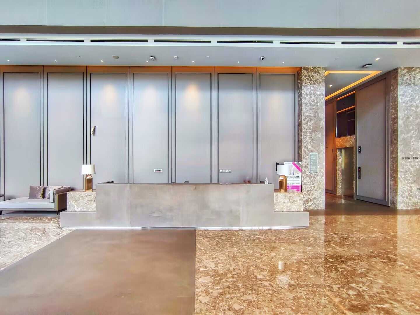 A modern reception area with a marble floor, a reception desk, and a seating area with a sofa and a lamp.