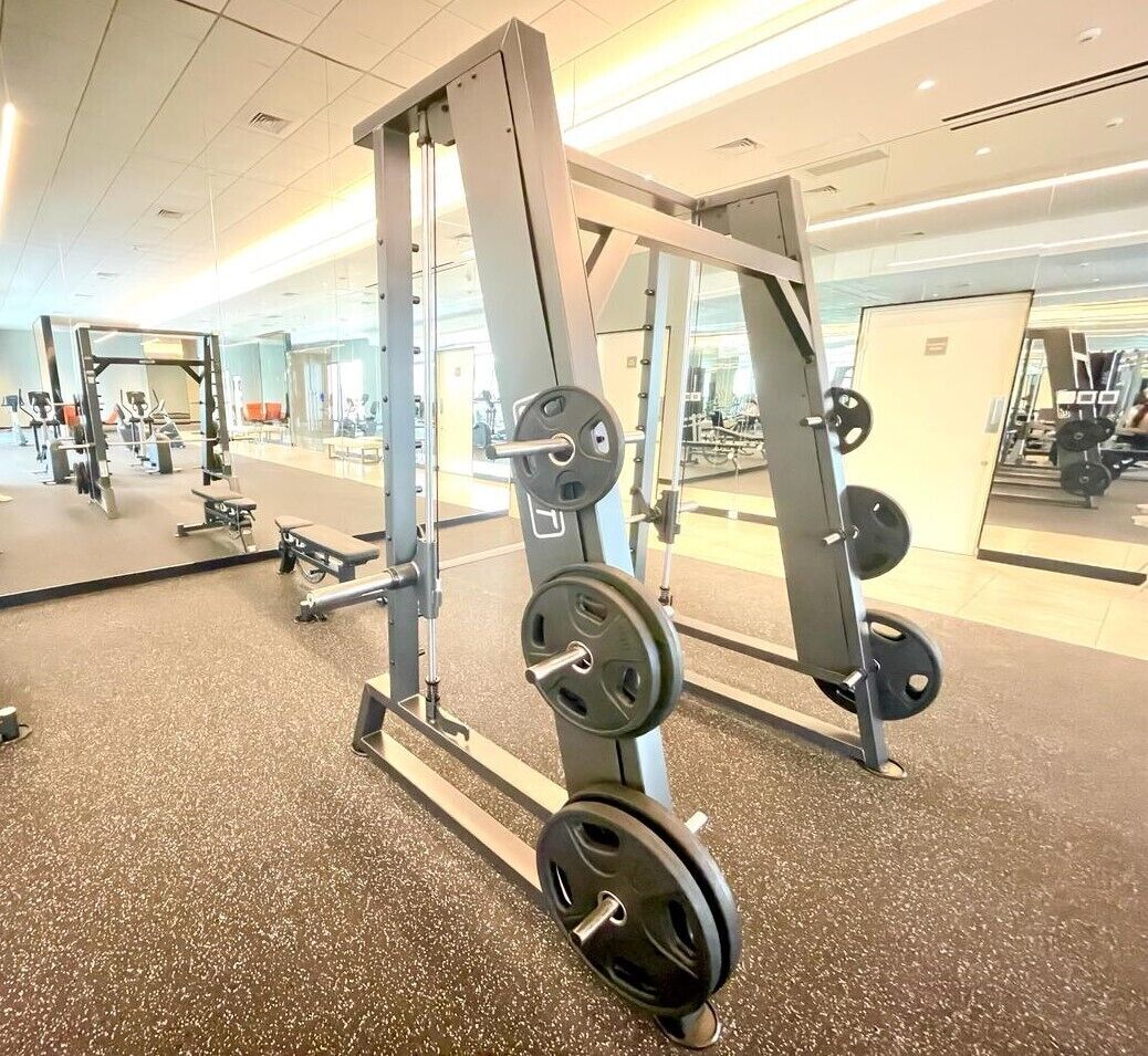 Une salle de sport équipée de matériel de musculation, de miroirs et dotée d’un sol recouvert de moquette.