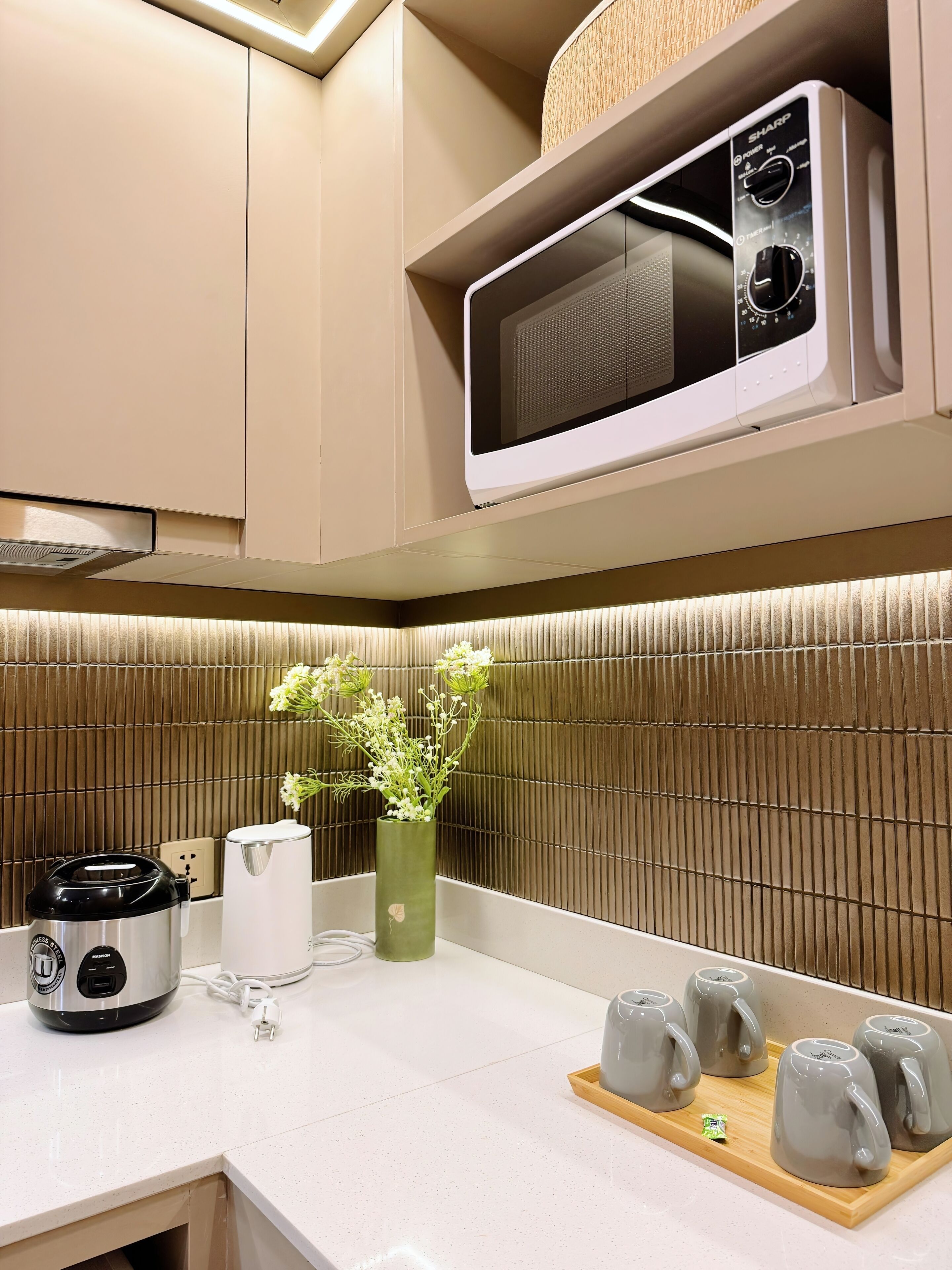 A modern kitchen with a microwave, a rice cooker, and a coffee maker.