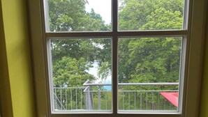 Une pièce dotée d’une grande fenêtre donnant sur un balcon agrémenté d’une marquise rouge et de balustrades en métal.