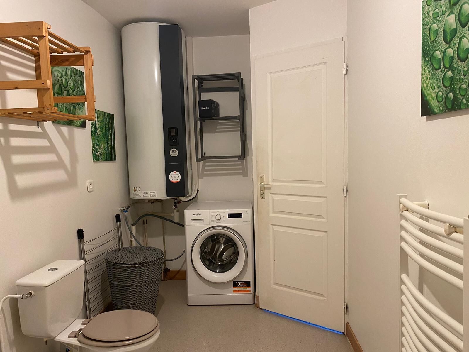 Et lille badeværelse med toilet, vaskemaskine og varmtvandsbeholder.