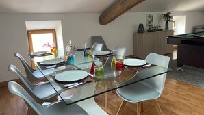 A dining area with a glass table, white chairs, and a pool table in the background. - Billiards Lounge loft with Billiards & Netflix by BoookingFuté (Socourt)