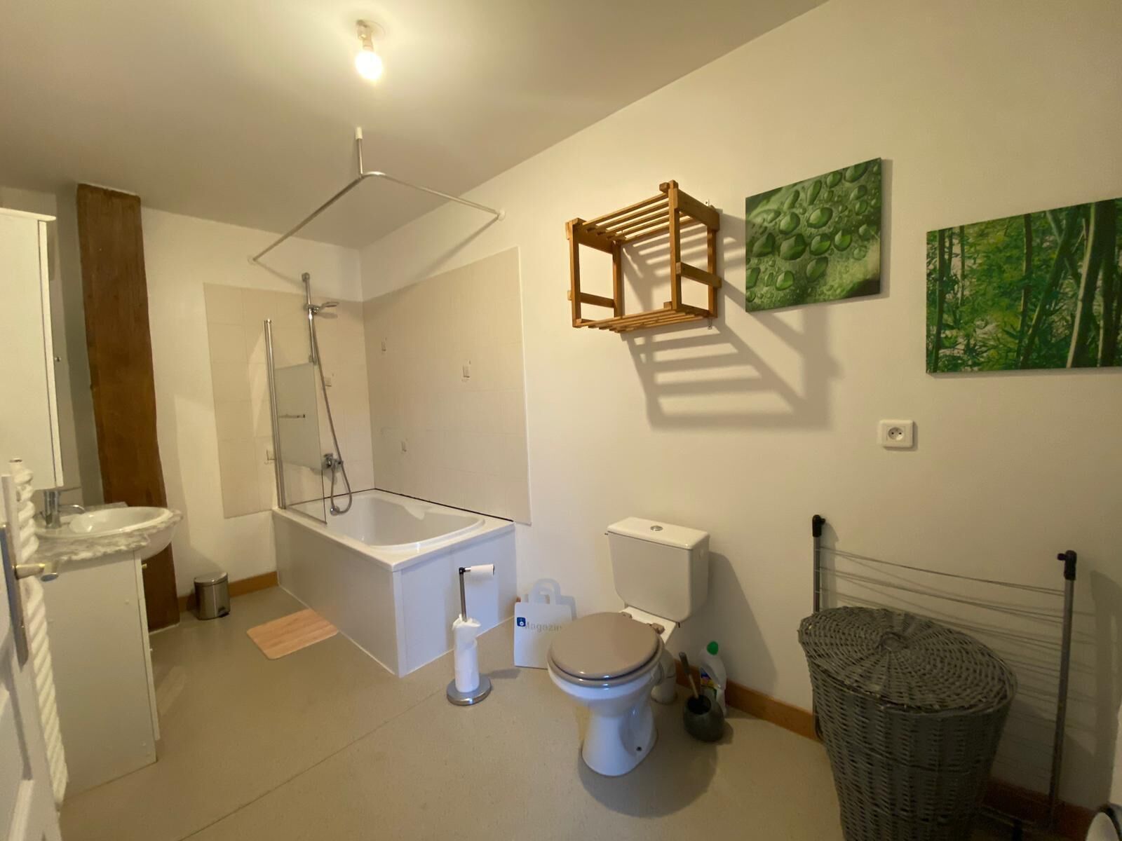 Et moderne badeværelse med badekar, toilet og bruser. To væghængte håndvaske og et stort spejl.