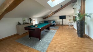 A spacious room with a pool table, a sofa, a television, and a large window. - Billiards Lounge loft with Billiards & Netflix by BoookingFuté (Socourt)