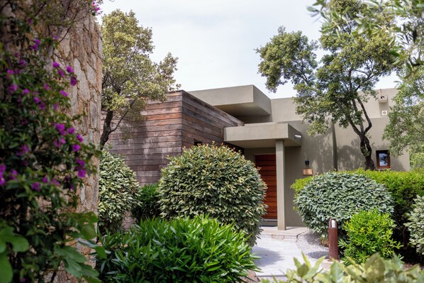 A modern building with a wooden facade, surrounded by well-maintained bushes and trees.