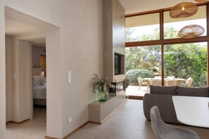 Ein modernes Wohnzimmer mit einer Couch, einem Couchtisch und einem groĂen Fenster mit Blick auf GrĂŒnflĂ€chen.