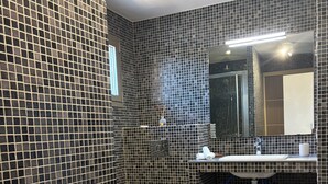 A bathroom with a tiled wall, a toilet, a sink with a mirror, and two towels on a shelf. - Villa with swimming pool, near Lozari beach – Corsica (BELGODÈRE)