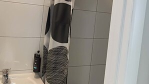 Un baño con un lavamanos blanco, una cortina de ducha estampada en blanco y negro, y una toalla blanca colgada en la pared.