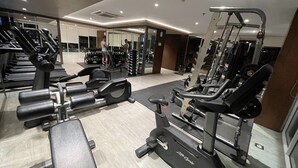 A gym with various exercise equipment including treadmills, weight machines, and free weights.