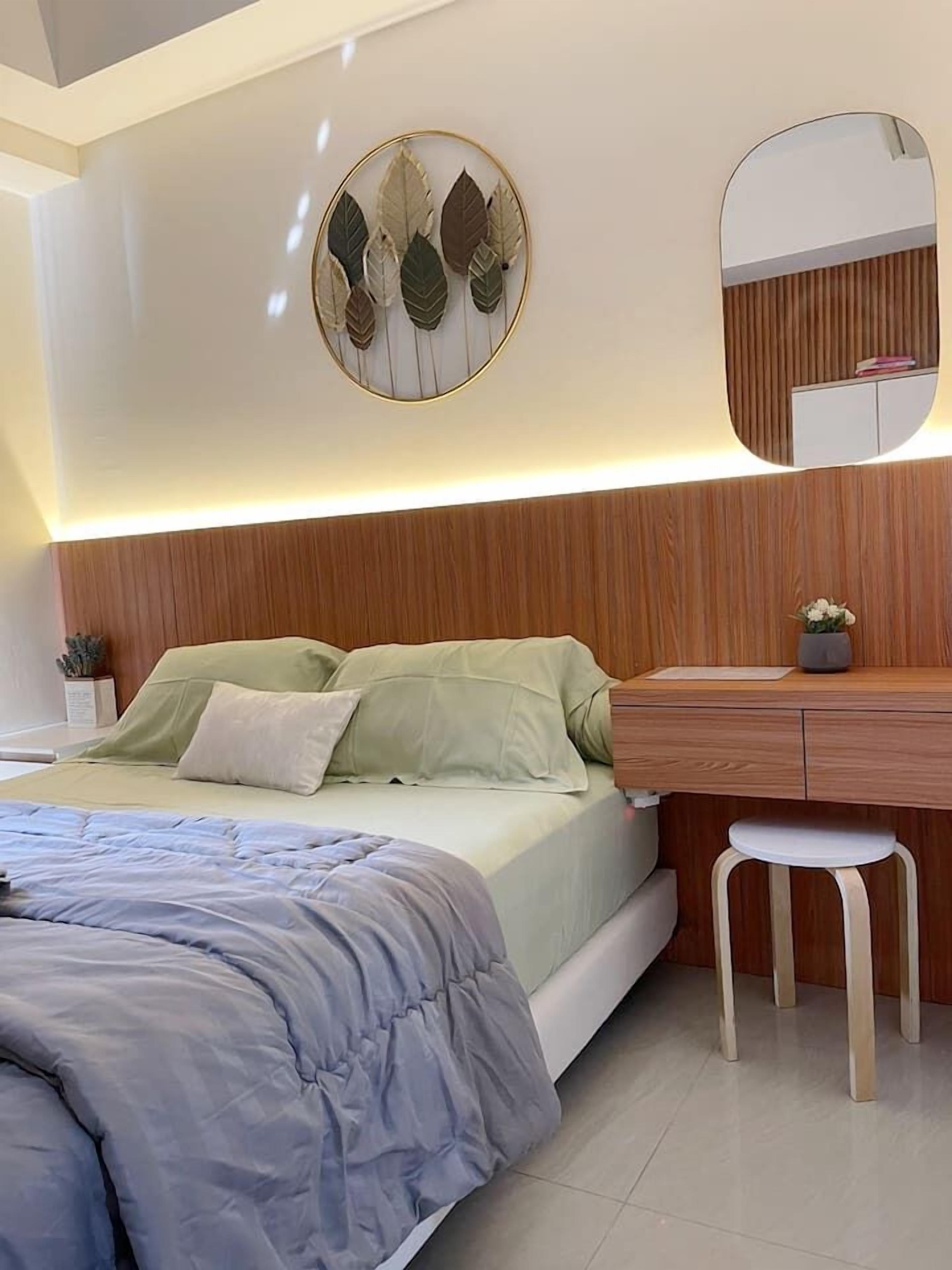 A modern bedroom with a bed, bedside table, and a mirror.