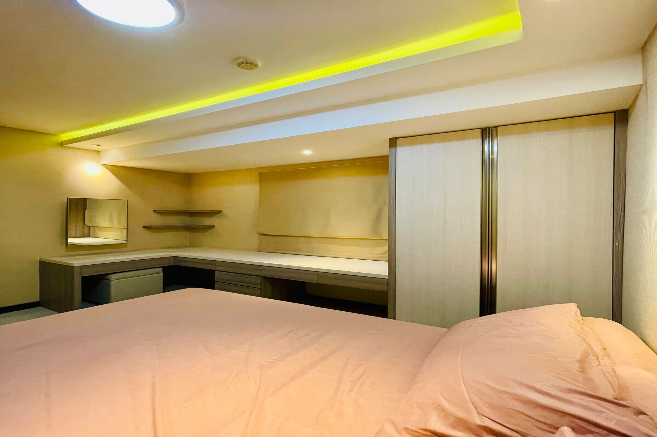 Une chambre d’hôtel moderne équipée d’un grand lit, d’un bureau, d’une coiffeuse avec miroir et d’une armoire.