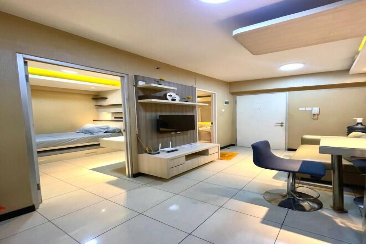 A compact hotel room with a bed, a TV, a small desk, and a chair.