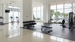 A spacious gym with large windows, a variety of exercise equipment, and a clean, modern design. - Sky Heaven Greenbay in North Jakarta (Jakarta)
