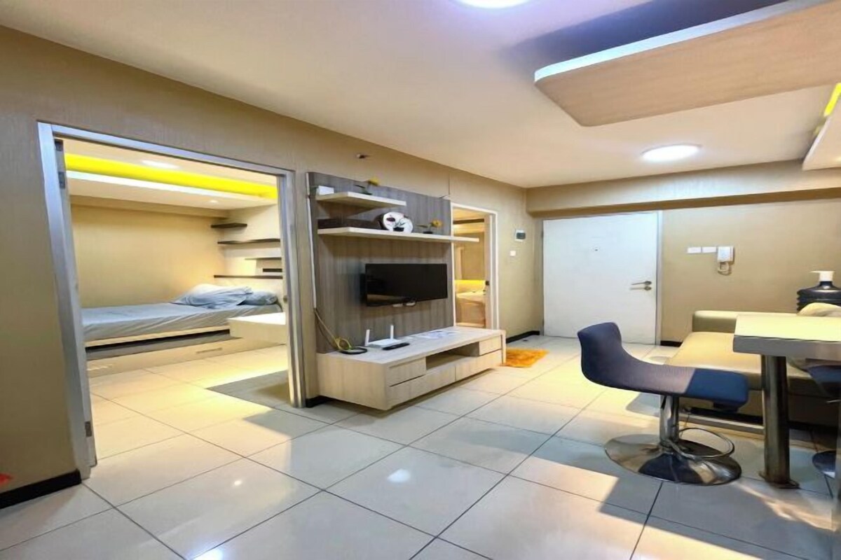 Habitación de hotel pequeña con cama, televisor, escritorio y silla.