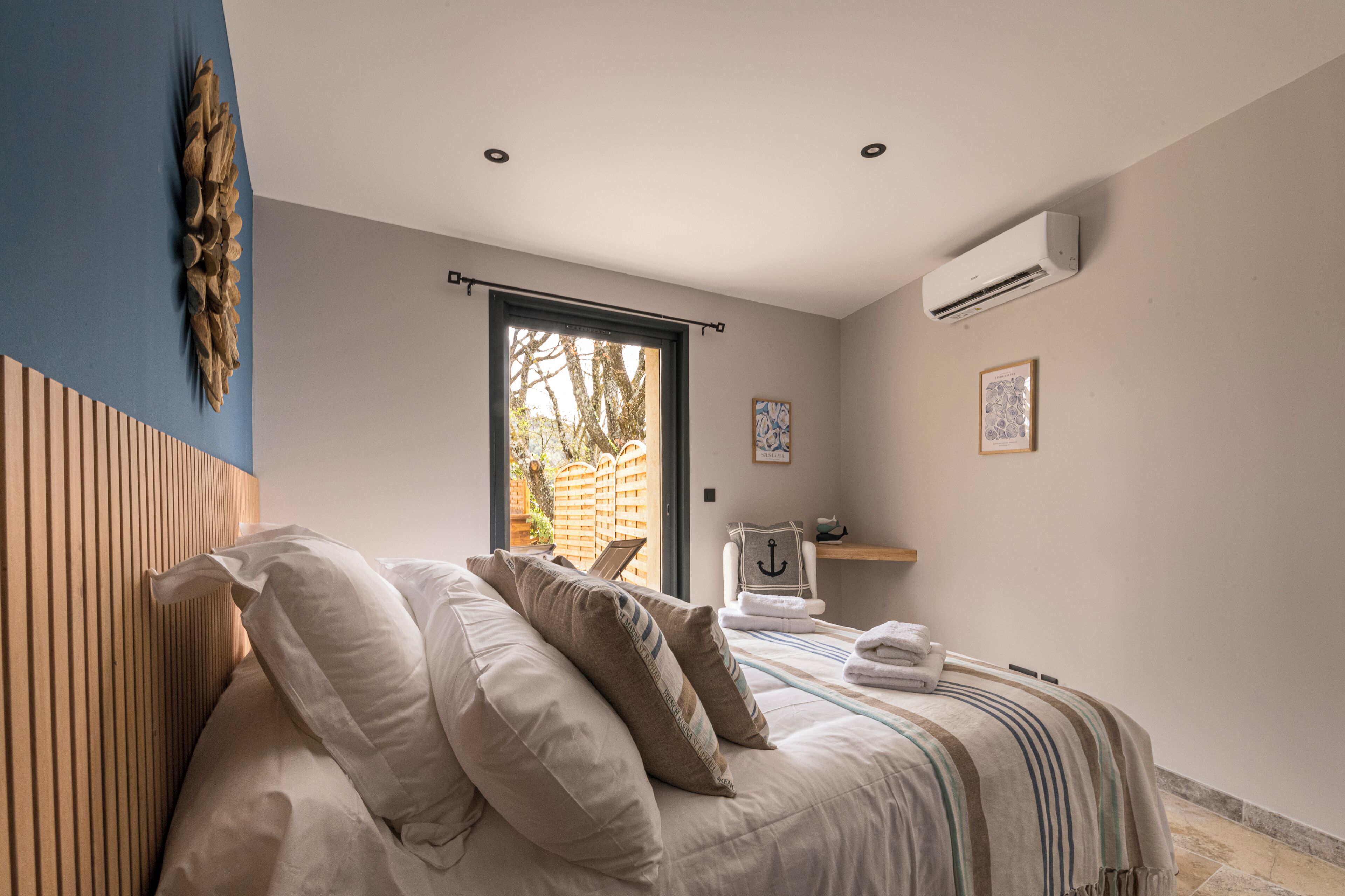 Un dormitorio con cama, almohadas, una ventana, un equipo de aire acondicionado y vistas al exterior.