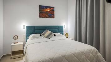 Une chambre à coucher avec un lit, une table de chevet, un tableau accroché au mur et une fenêtre avec des rideaux.