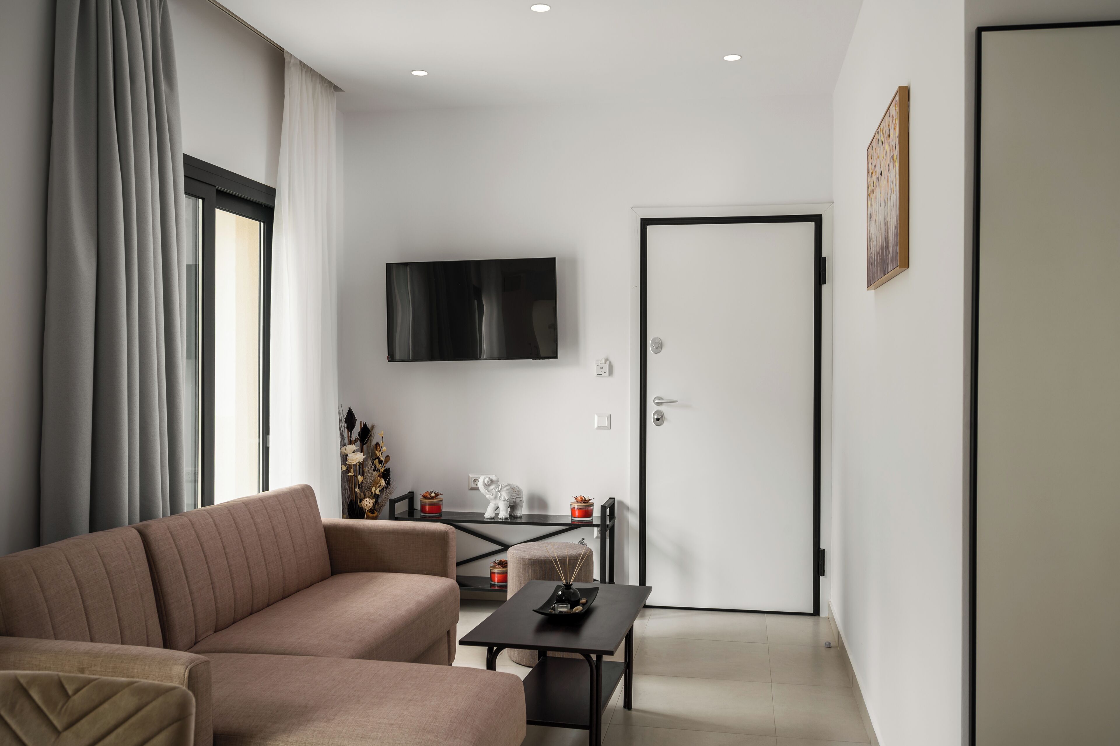 A modern living room with a sofa, a coffee table, and a TV mounted on the wall.
