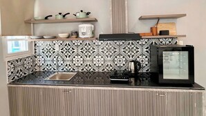 A compact kitchen with a black and white patterned backsplash, a stainless steel sink, and a built-in oven. - Rova Hotel & Apartment - Amalfi Sunset Town (Phu Quoc)