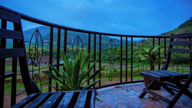 A balcony with a metal railing, a wooden bench, and potted plants.