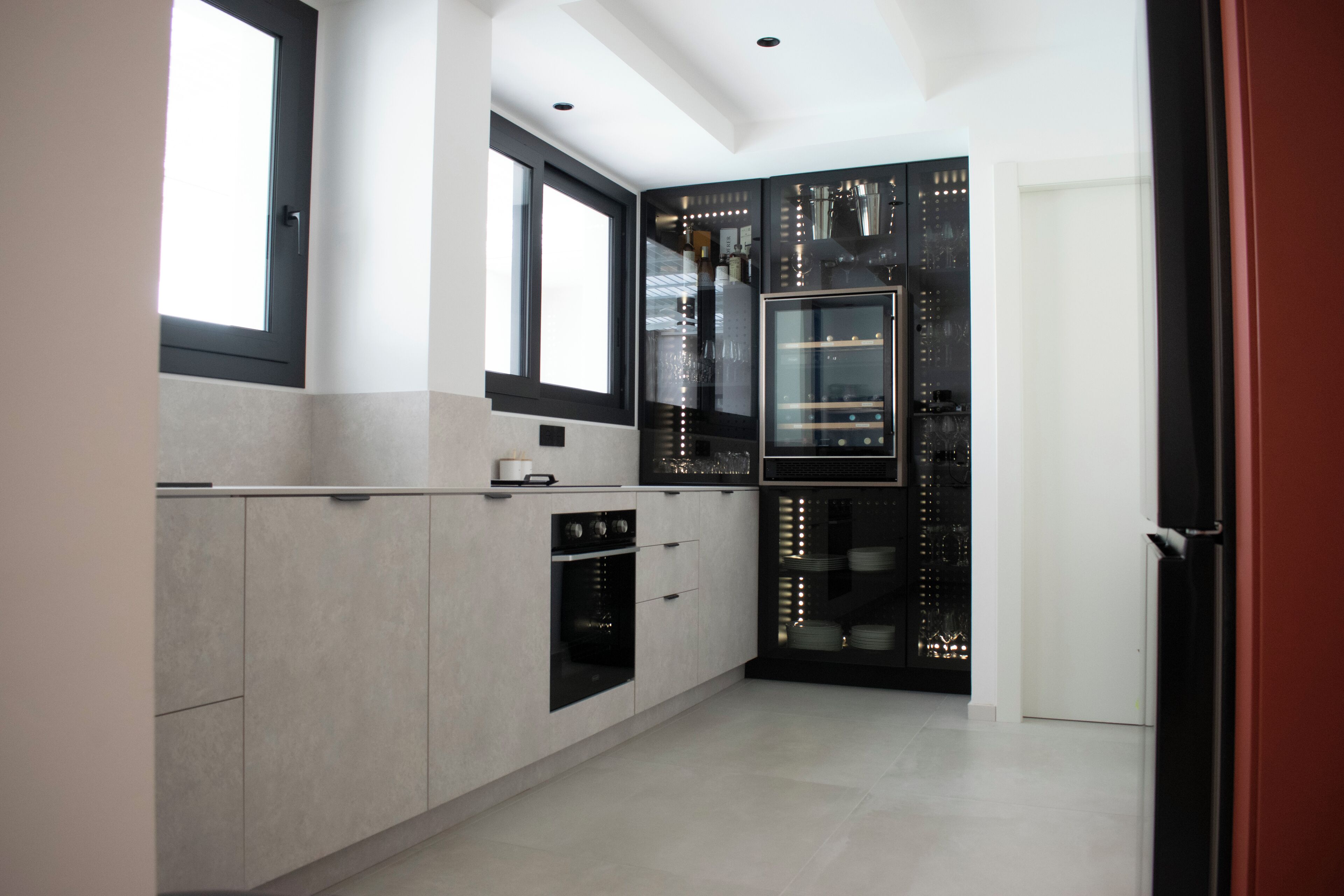 Een moderne keuken met een groot raam, een ingebouwde oven en een zwarte koelkast.