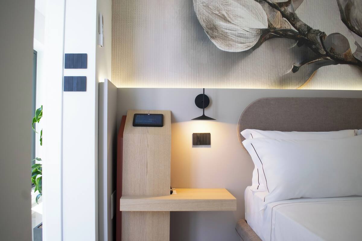 Une chambre à coucher moderne avec un lit, une table de chevet et une lampe fixée au mur.
