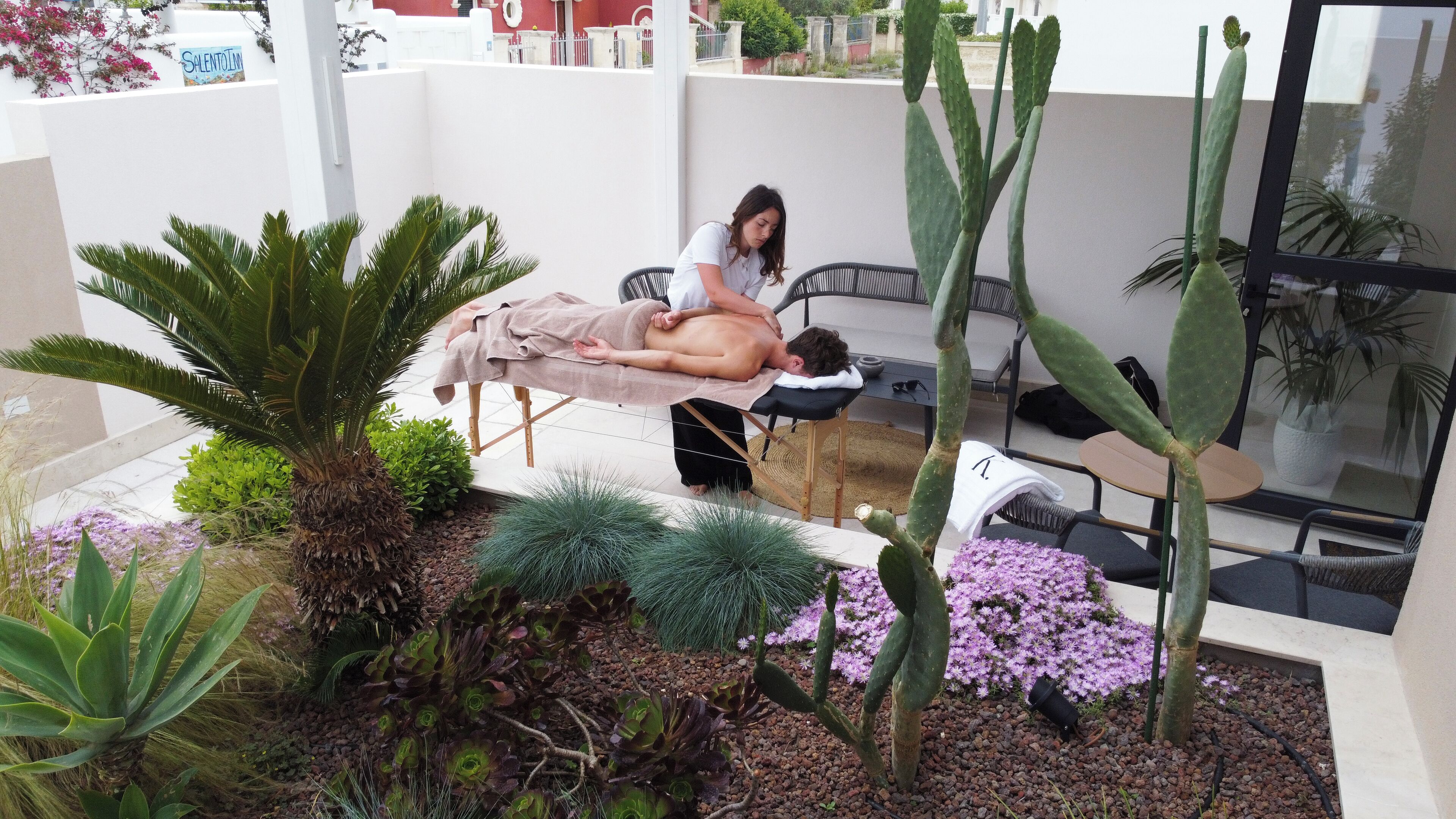 A man receiving a massage in a room with a view of a garden.